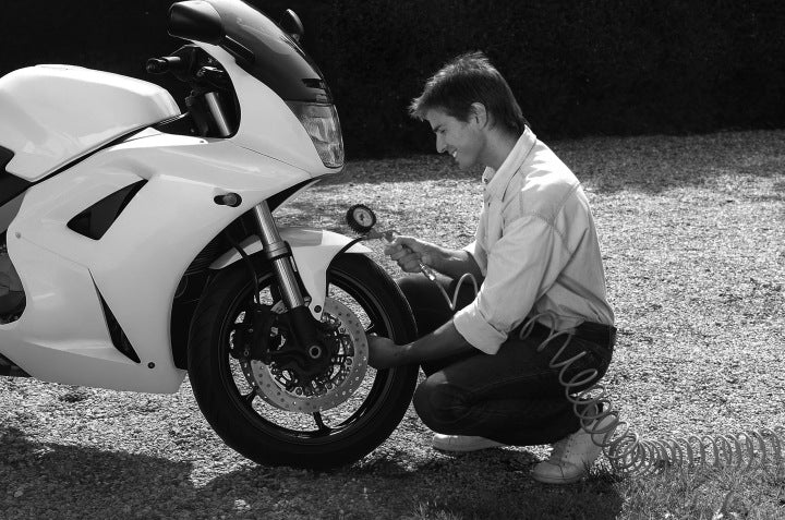 Motocykl sportowy z osobą klęczącą przy oponie i kole